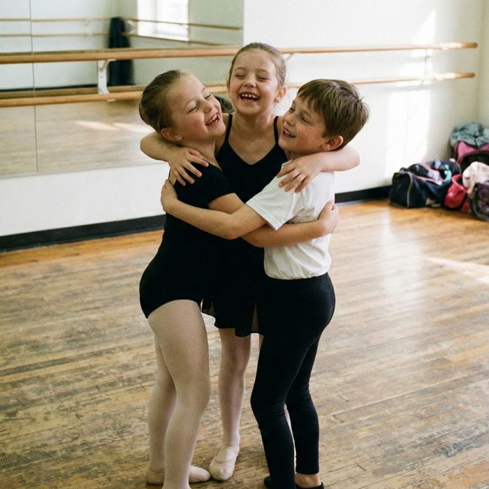 Three young dancers hugging joyfully after finishing a routine