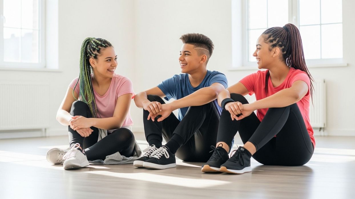 teenage dancers sit together on the floor of a sunlit studio