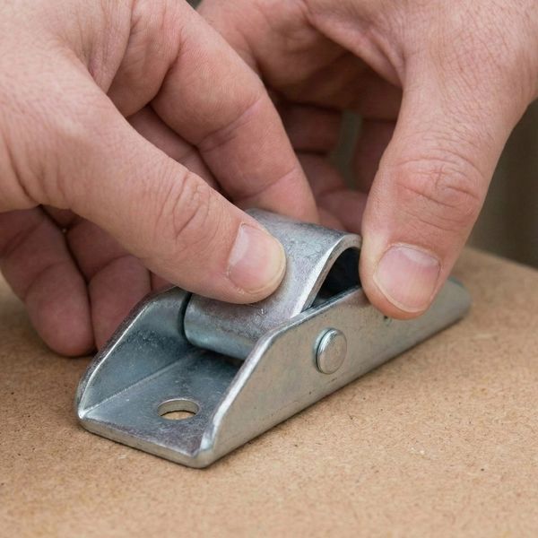 Close-up on hand checking a metal home tie-down Close-up on hand checking a metal home tie-down