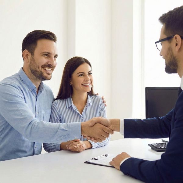 A happy couple shakes hands with a loan officer