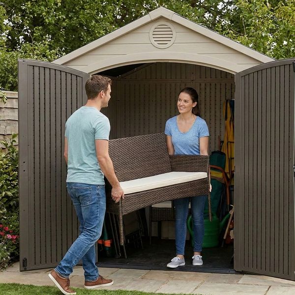 Couple carrying patio furniture into a storage shed Couple carrying patio furniture into a storage shed