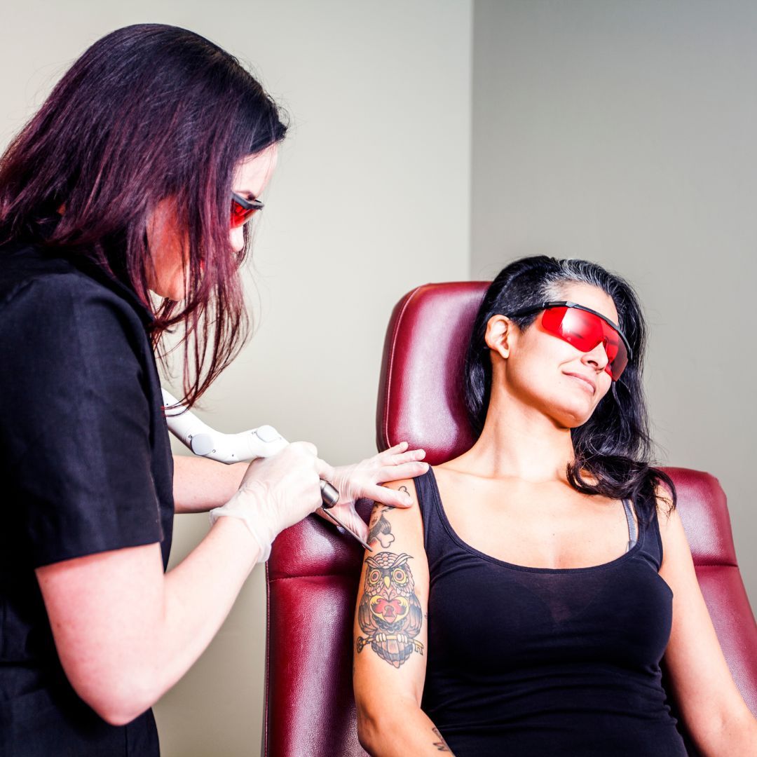 tattoo removal technician looking at client's arm