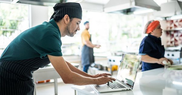 Chef in commercial kitchen on computer