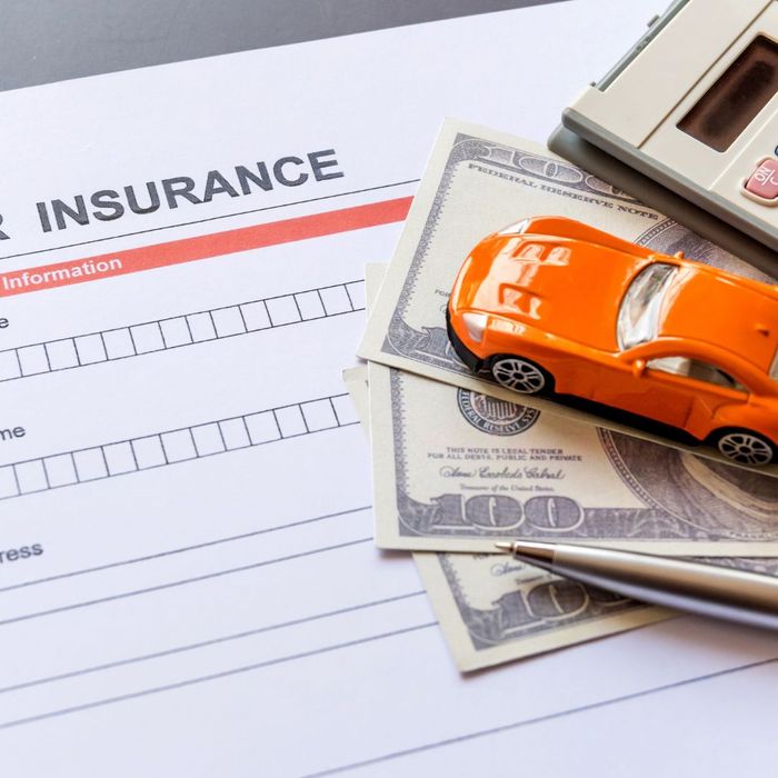 Car insurance paper with toy car, cash, and calculator 