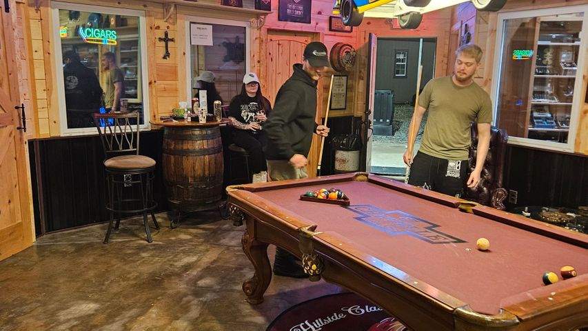 People playing pool in a cigar lounge.