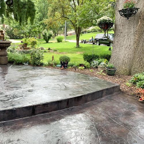 a concrete patio with a tree and a fountain