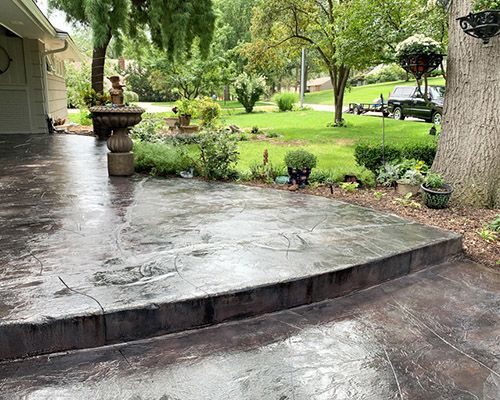 a concrete patio with a fountain and trees