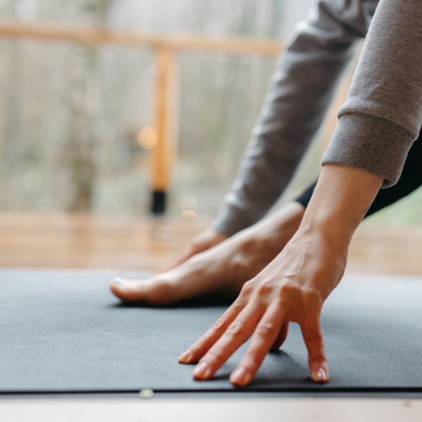 Close up of hands and foot on yoga mat