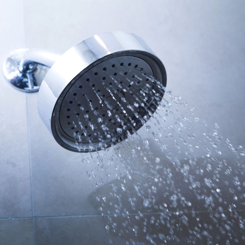A chrome showerhead with multiple streams of water spraying downward.