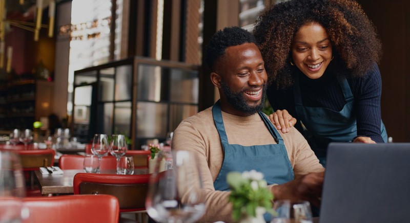 smiling business owners looking at laptop