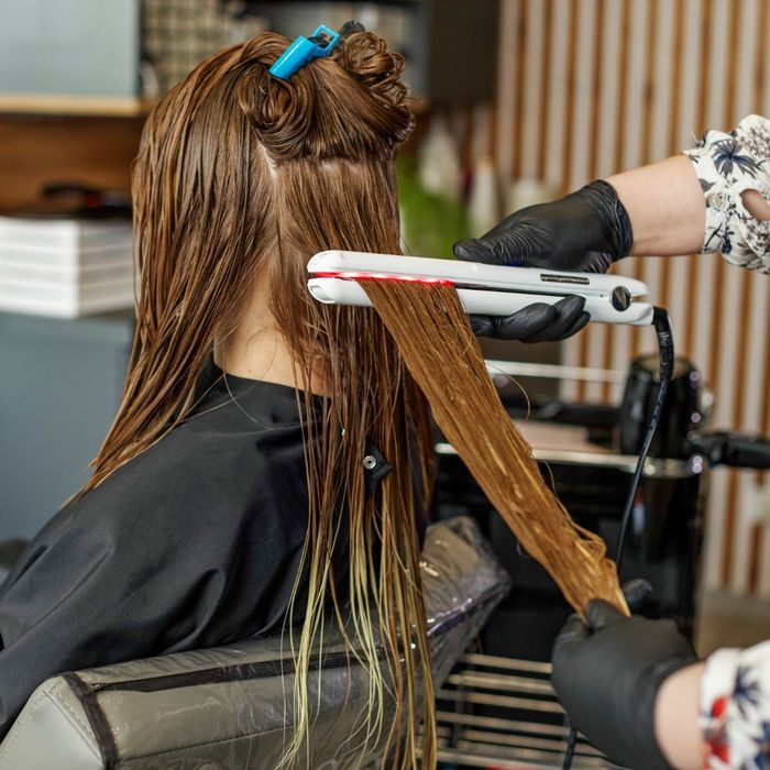 Hair professional using a hair straightener on wet hair. 