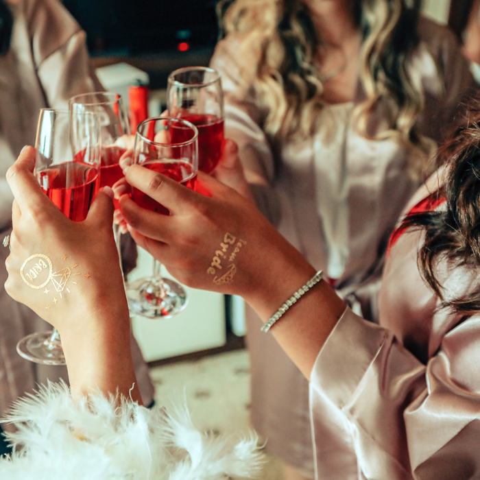 bride clinking glasses with her bridal party. 