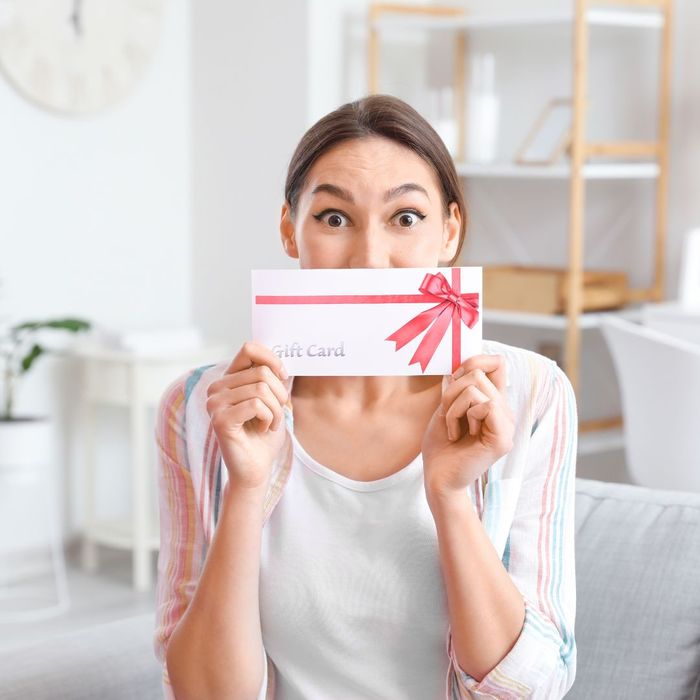 Woman excitedly holding up a gift card.