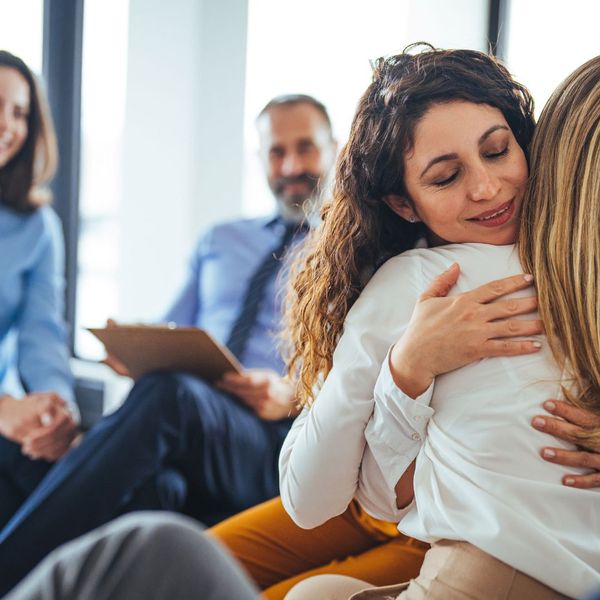 Group therapy hug with supportive, smiling participants