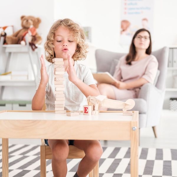 therapist watching little boy stack wood blocks therapist watching little boy stack wood blocks