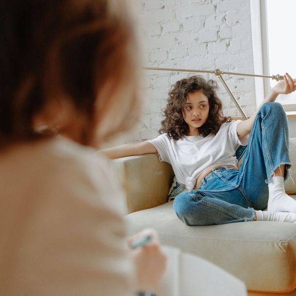 Young woman lounging casually, speaking to another person