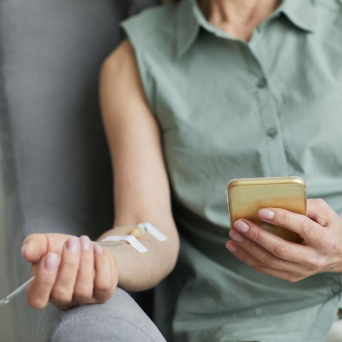 person scrolling on phone while receiving iv therapy 