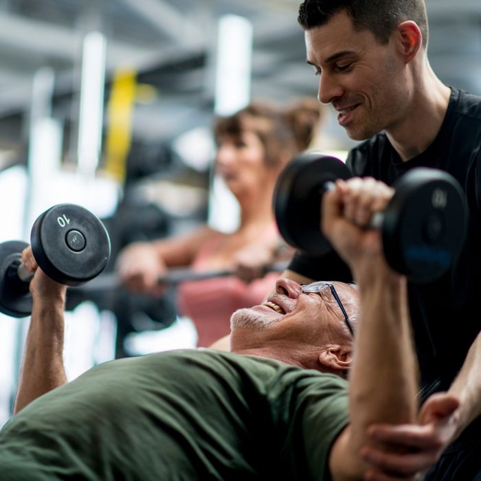 Fitness trainer assisting a man with bench press