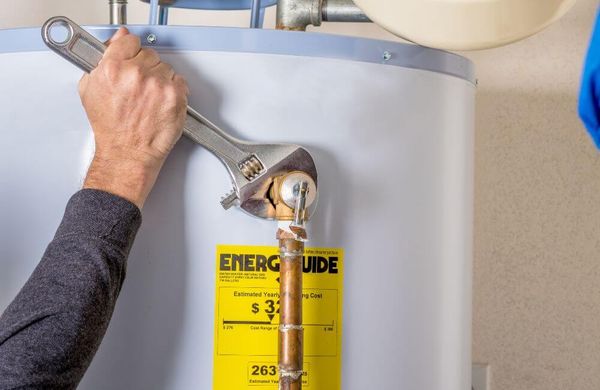 person adjusting pipes on gas water heater