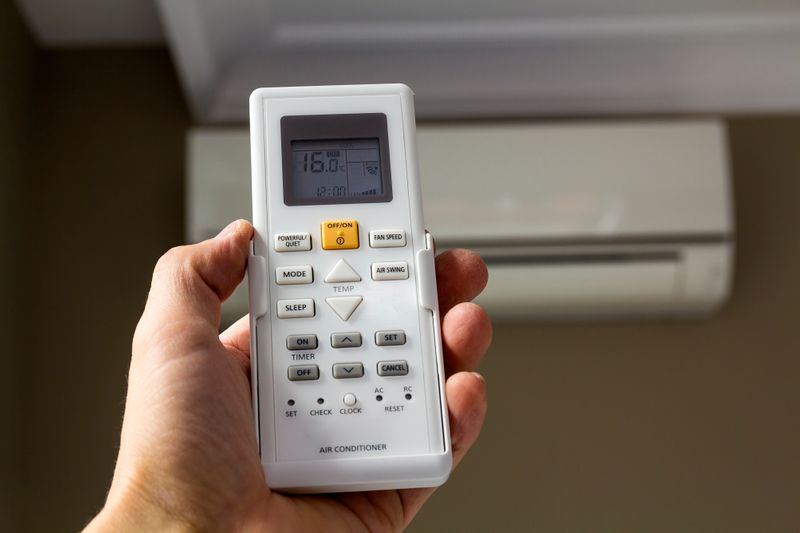 hand-holdind-control-switch-of-home-air-conditione-2023-11-27-05-32-05-utc.jpg