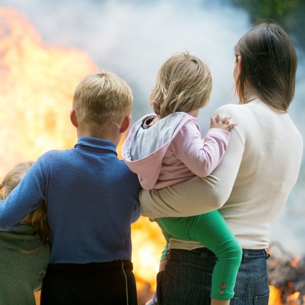 young family standing near campfire young family standing near campfire
