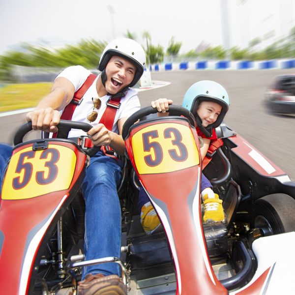 father and child riding go kart together father and child riding go kart together