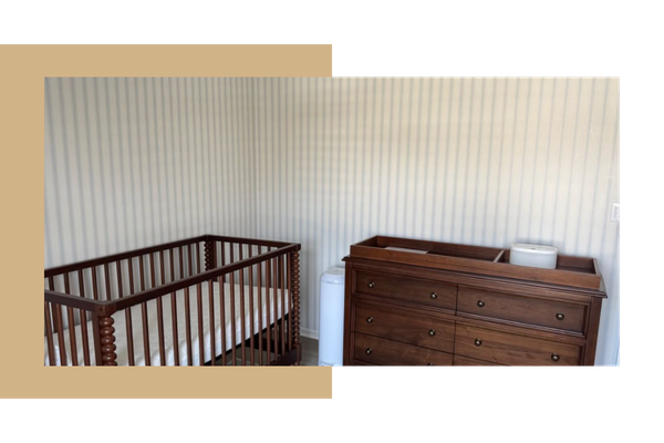 Nursery with striped wallpaper behind the dresser and crib