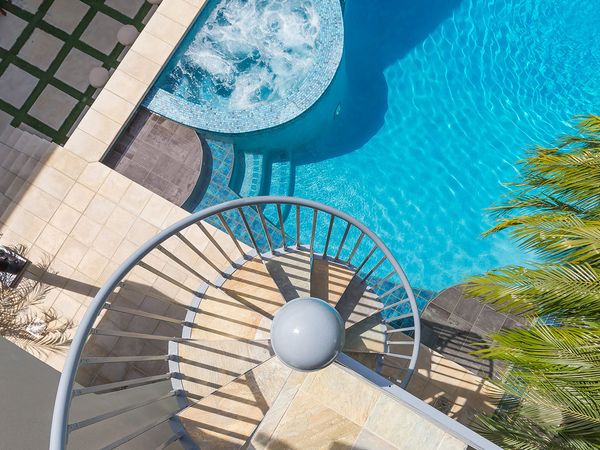 Top-down image of an exterior spiral staircase and outdoor pool