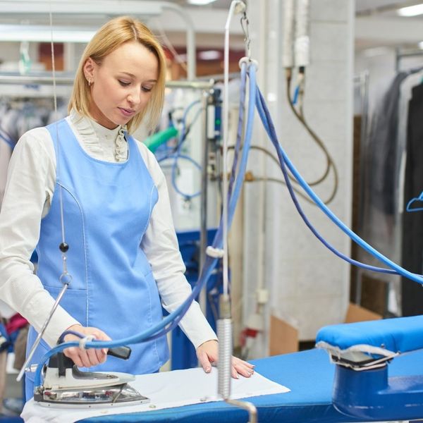dry cleaner pressing and steaming a shirt