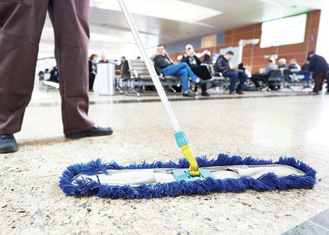 a worker mopping the lobby of an airport or commercial building