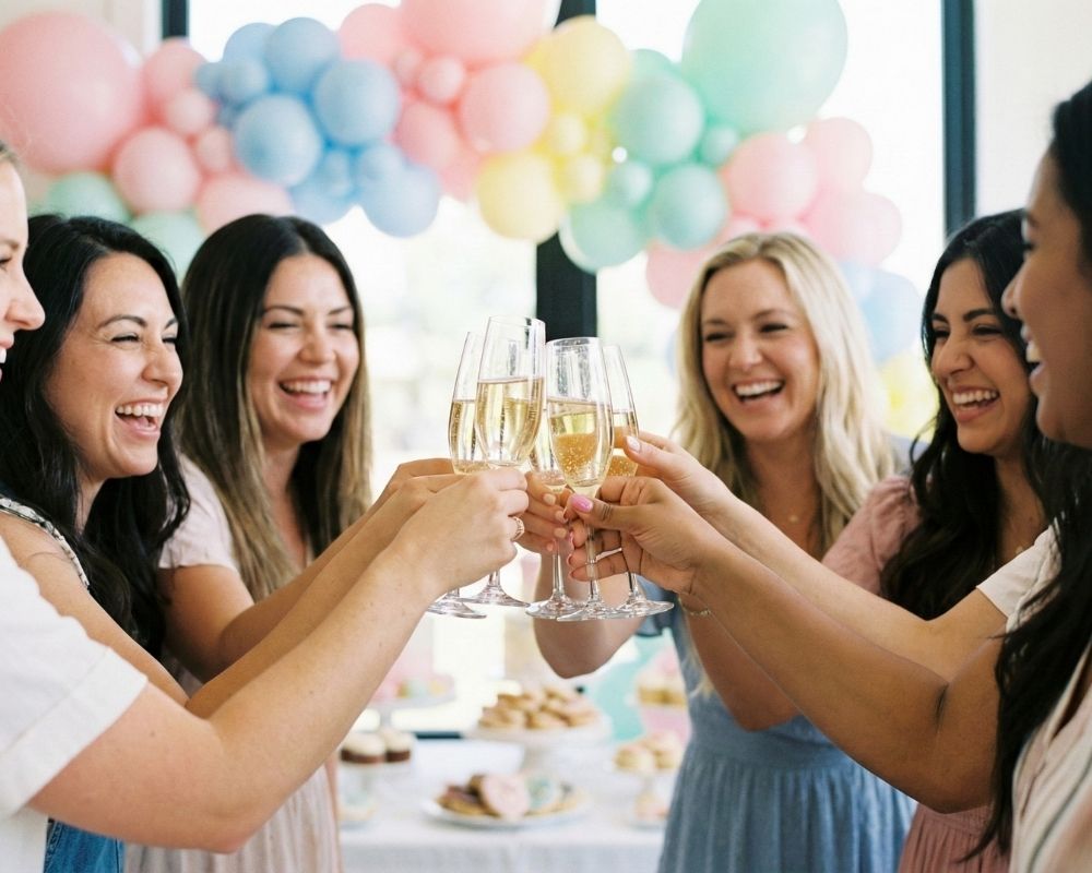 Close-up of a group of diverse women toasting with champagne glasses at a celebratory brunch or party.