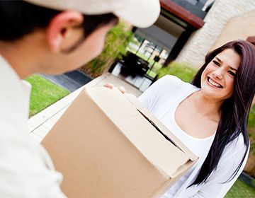 Woman smiling and handing a box to a mover