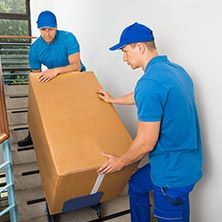 Movers moving a large box down stairs