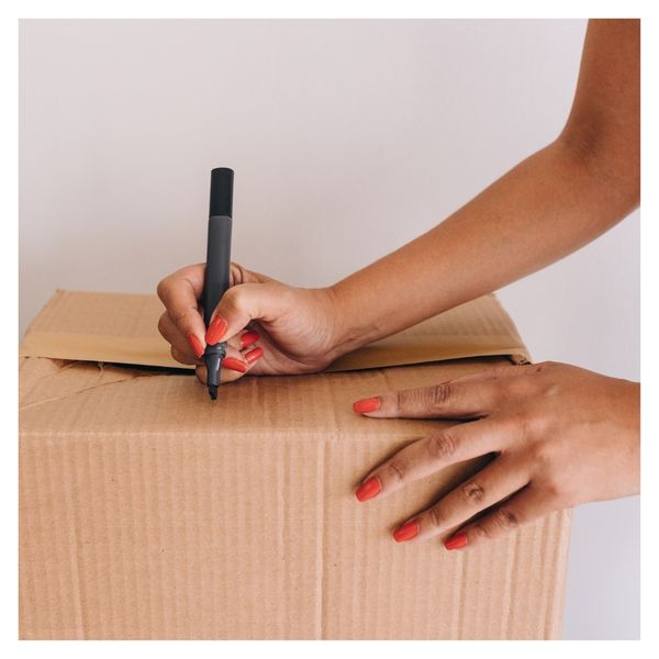 Woman writing on a cardboard box