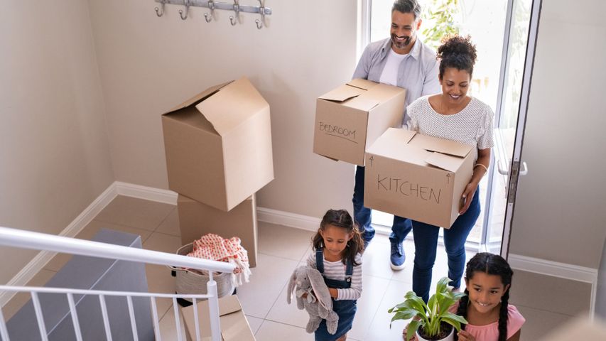 Family carrying moving boxes into a house