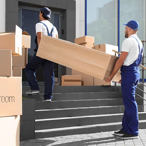 Movers moving a large box up stairs