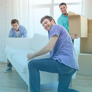 Movers smiling moving boxes and a couch