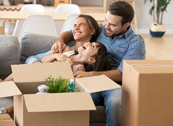 family smiling sitting on the couch surrounded by moving boxes