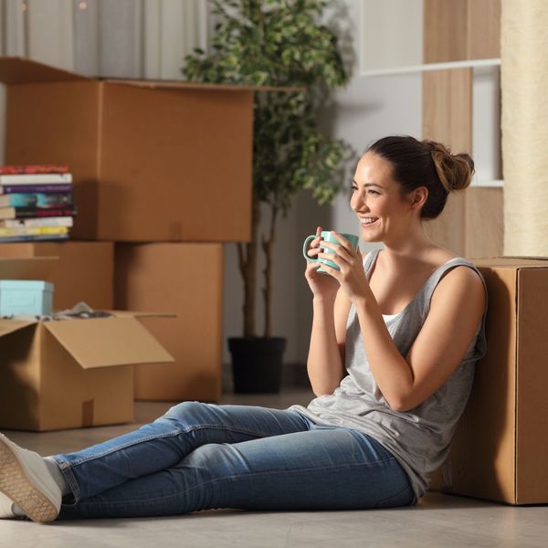 Woman sitting on floor with boxes smiling