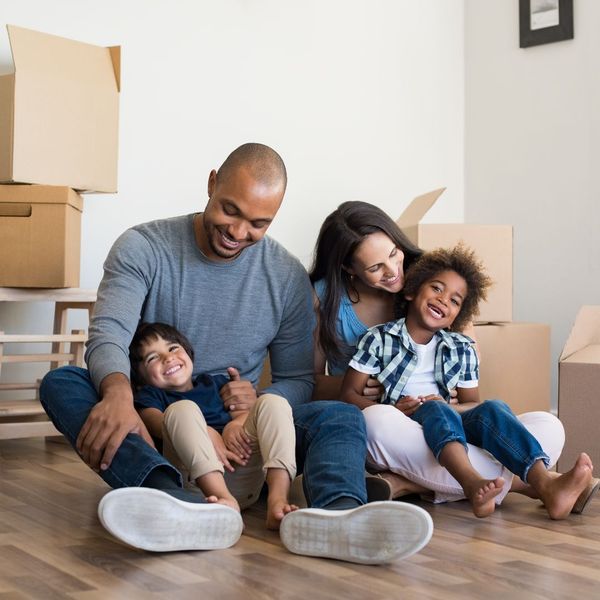 Family smiling in empty house with boxes around them