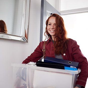 Young woman walking into her new home with a moving box