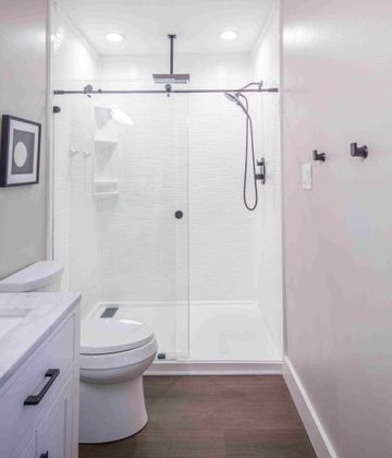 Onyx-white-wavy-tile-panels-trench-style-drain-barn-door-single-bypass-shower-with-disc-handle-Kohler-skirted-toilet-marble-vanity-top-LVP-floor-eight-hour-shower.jpg