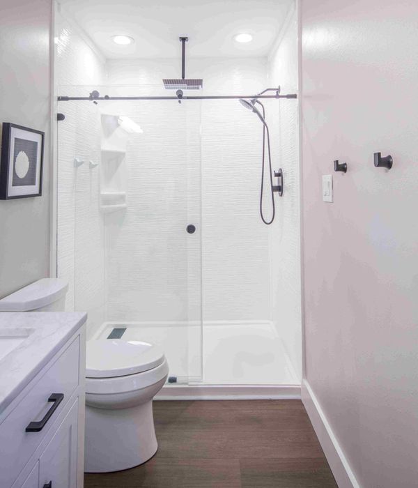 Onyx-white-wavy-tile-panels-trench-style-drain-barn-door-single-bypass-shower-with-disc-handle-Kohler-skirted-toilet-marble-vanity-top-LVP-floor-eight-hour-shower.jpg