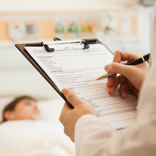Doctor looking over medical chart of patient in the hospital