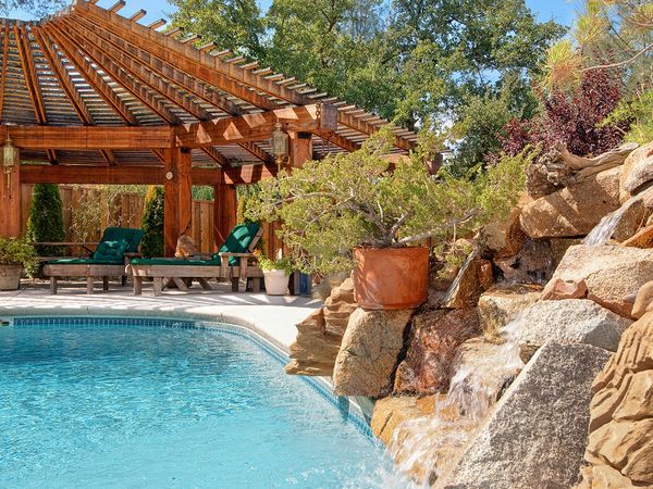 Image of a backyard swimming pool with a large rock feature featuring a waterfall.