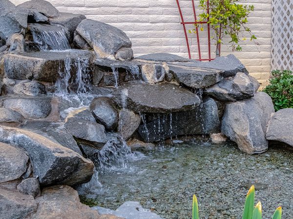 Image of a custom backyard water feature with a stone cascade waterfall.