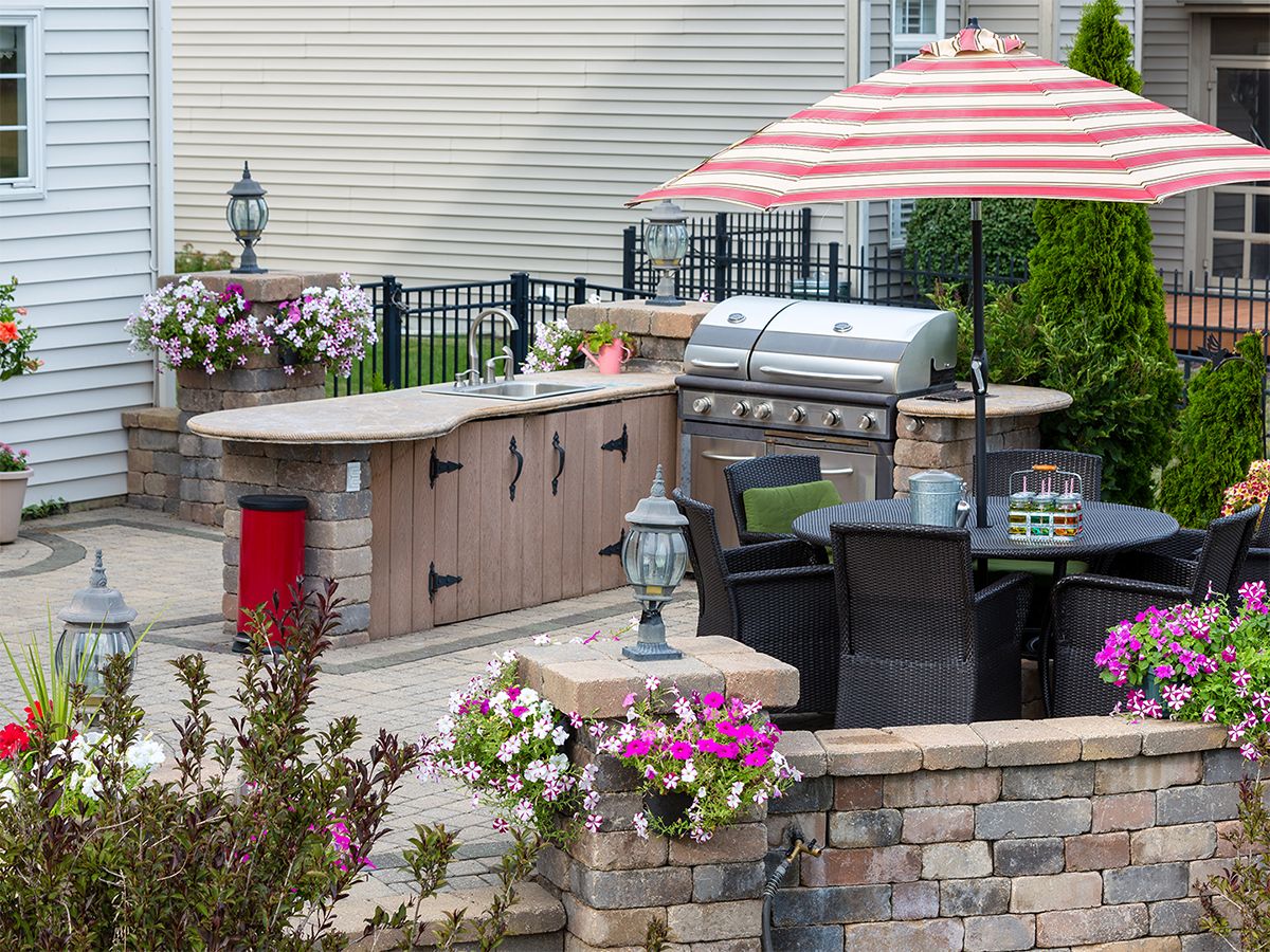 Image of a luxurious outdoor kitchen area with a sink, grill, and table.