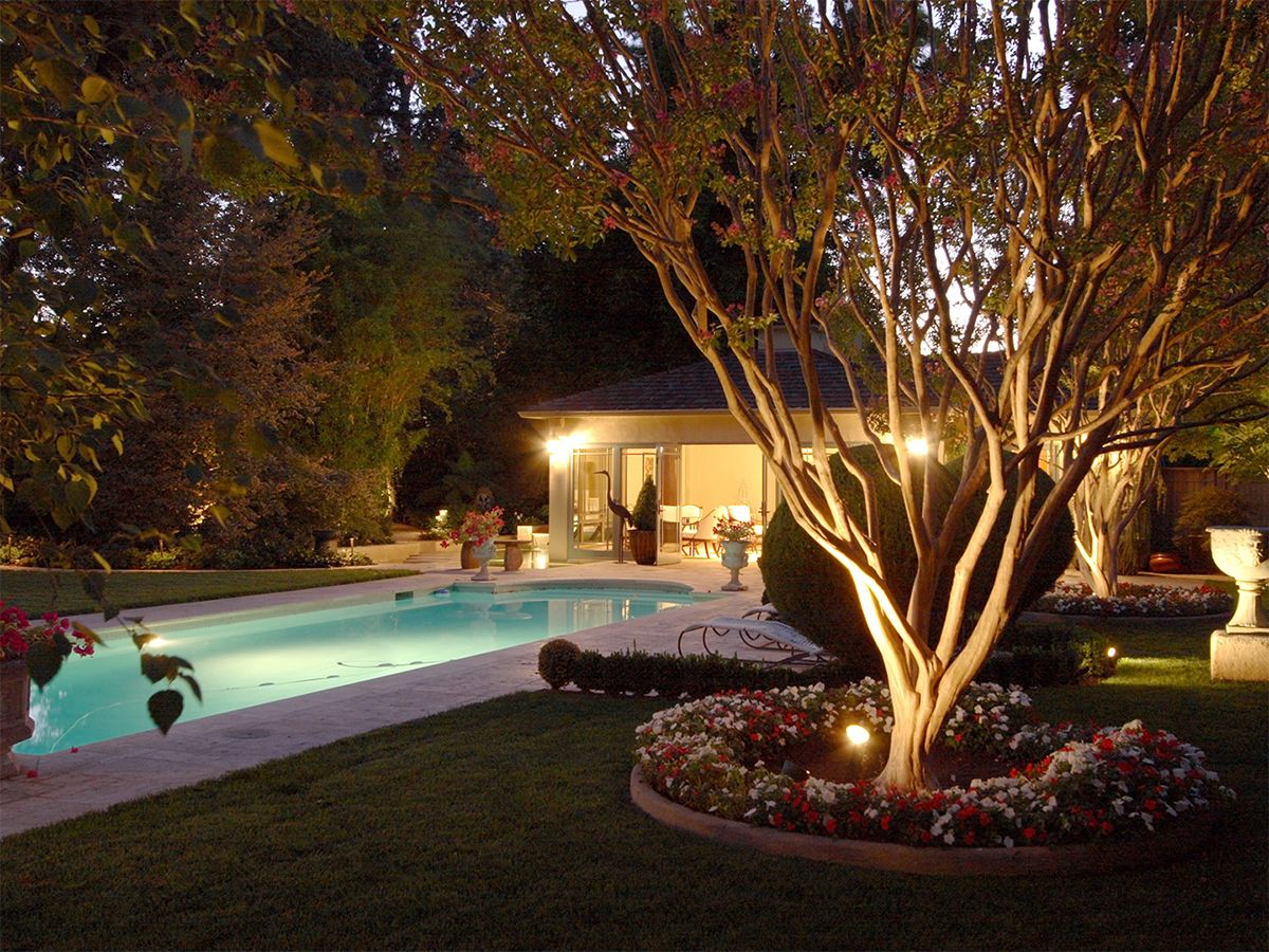 Image of a luxurious backyard featuring a swimming pool and an outdoor lighting system.