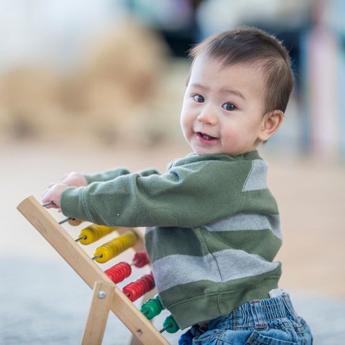 a toddler playing with an abacas