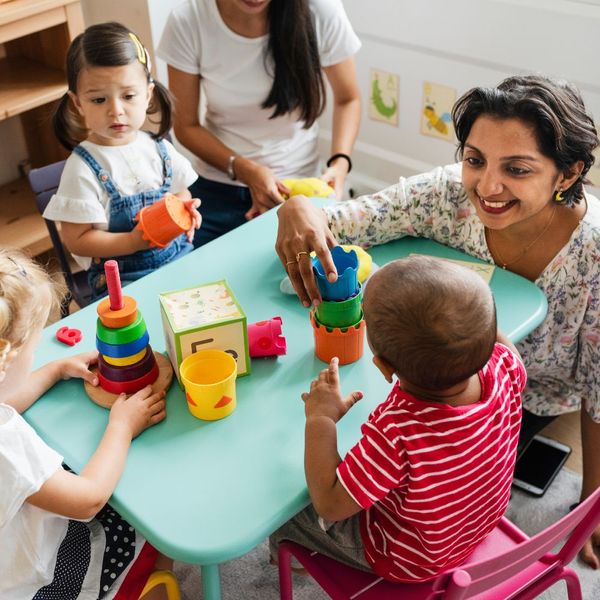 two daycare workers playing with children at a table